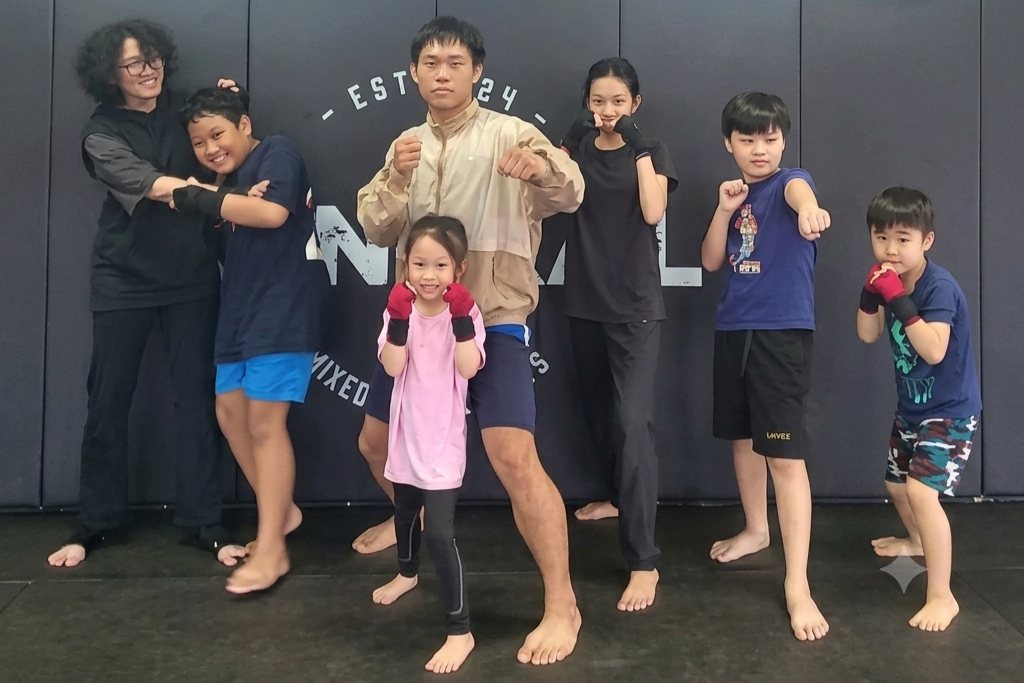 Group photo of coaches and kids students posing together at Central MMA